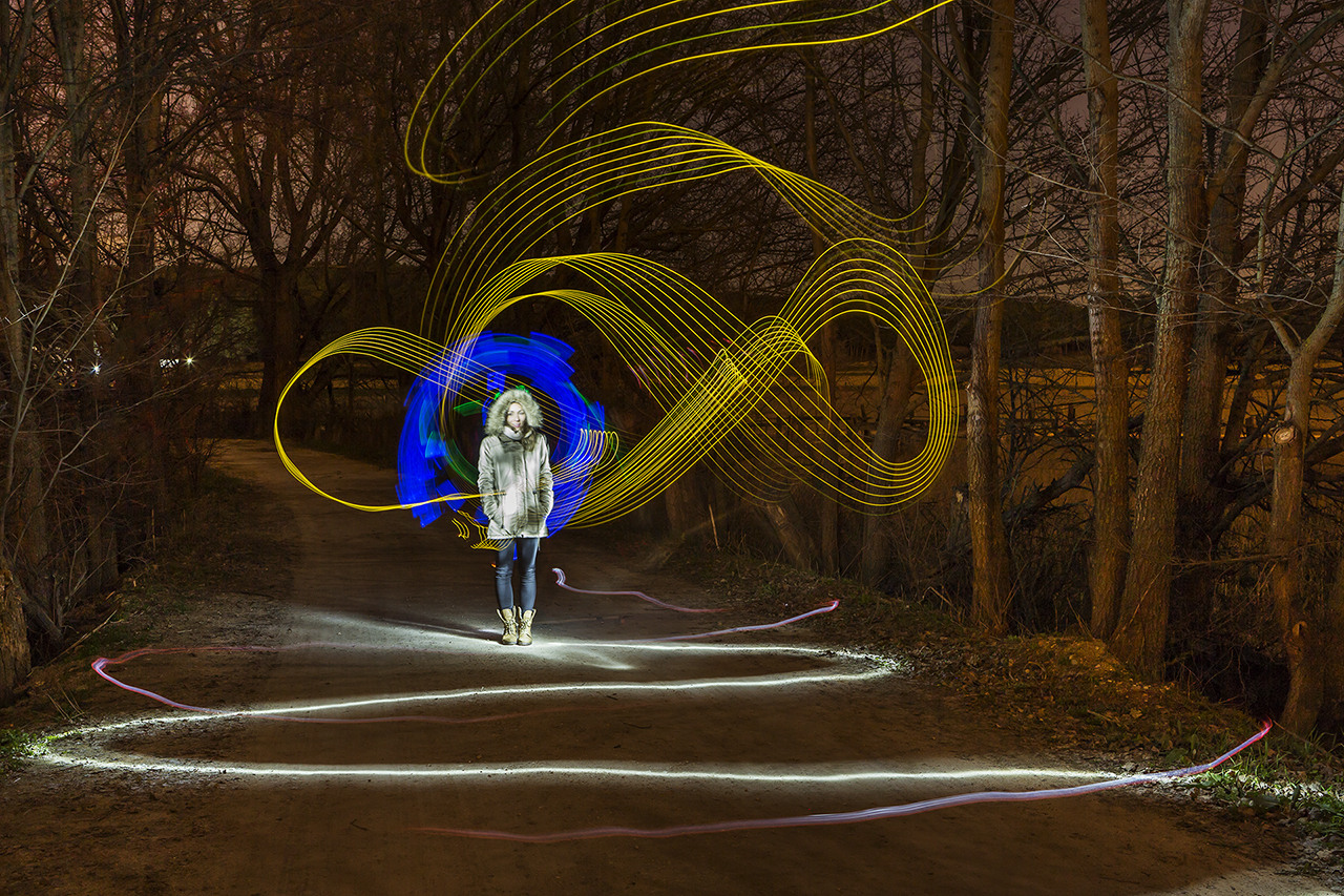 Lightpainting. Chica posando en la noche con estelas de luz.